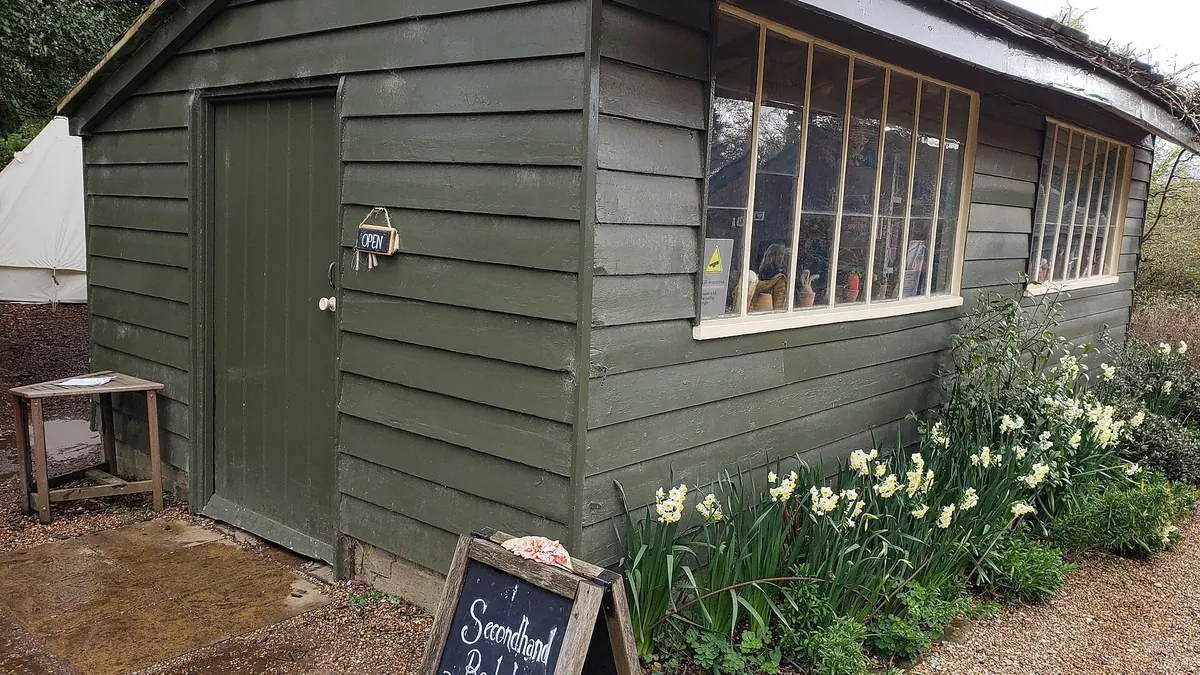 A small second-hand bookshop in a green wooden hut in a garden